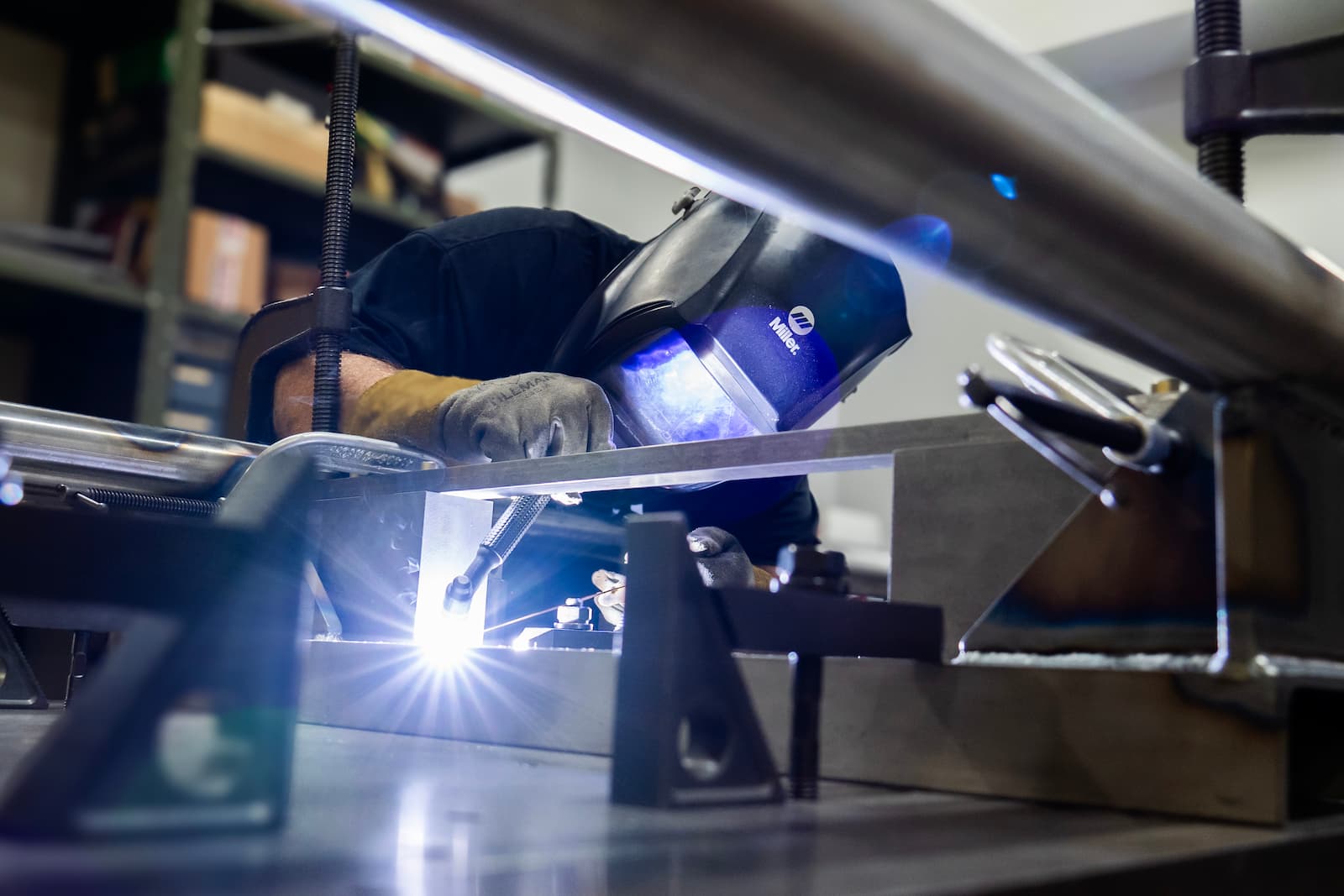 A person wearing a welding mask while welding in a machine shop.