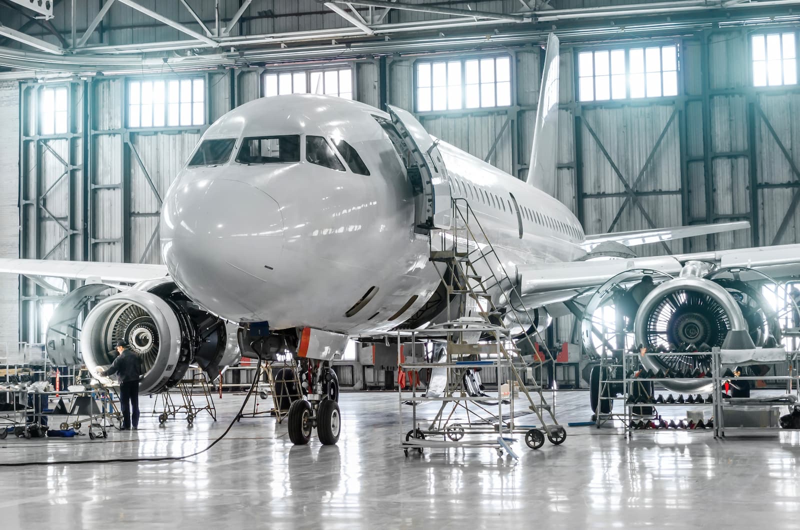 Airplane undergoing maintenance in a spacious hangar.